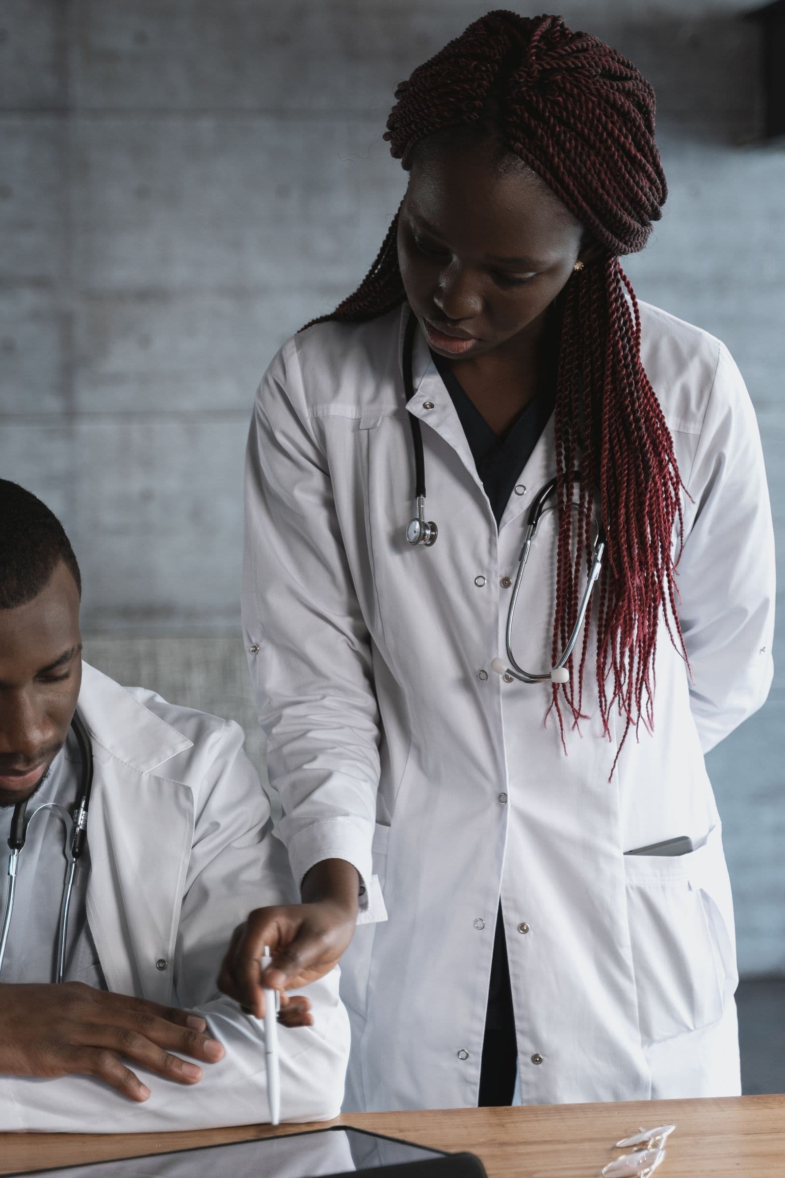 Two clinicians in white coats reviewing notes together at a table